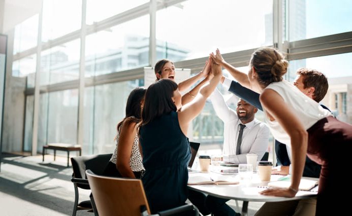 A group of adobe commerce pwa development experts high-fiving a successful launch