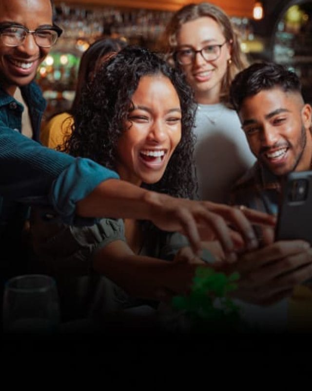 A group of friends laugh at a phone screen