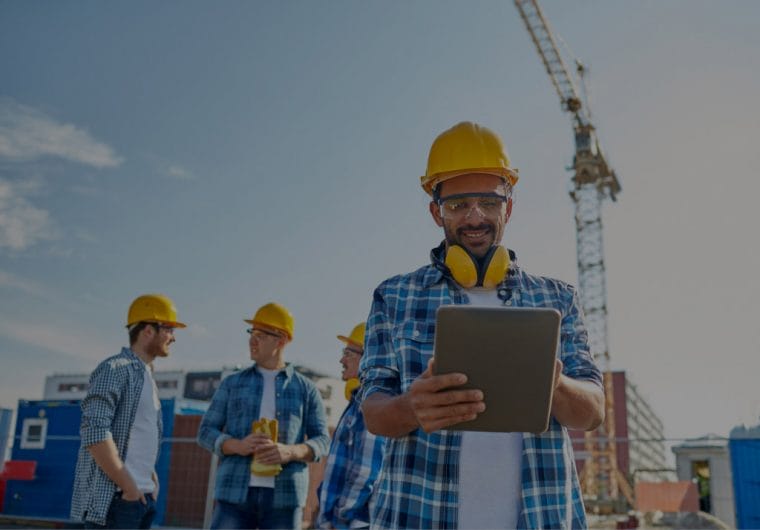 Construction workers smile and talk with hardhats on