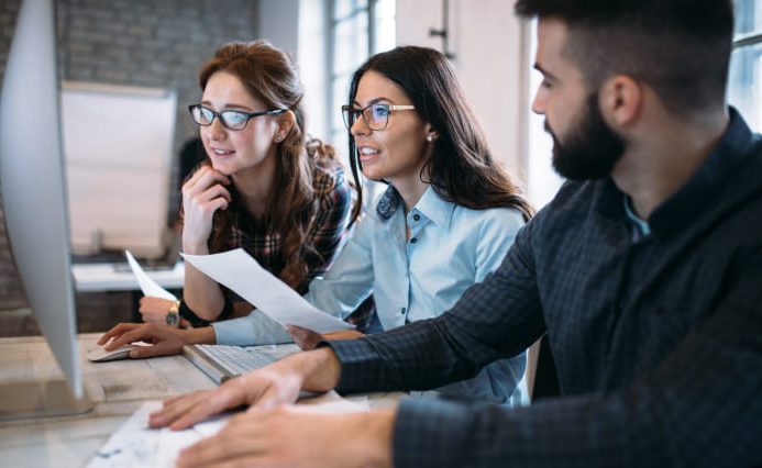 Three real estate website design company employees sit at an office desk