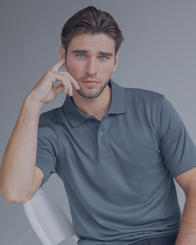 A man poses in a grey polo shirt