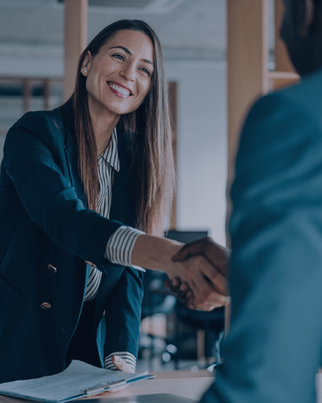 A woman in a suit shakes a man's hand